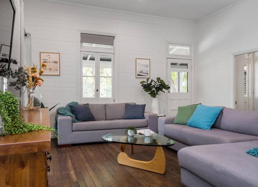 Cove Studios in Byron Bay living room with gray sectional sofas, glass coffee table, and bright white walls.