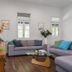 Cove Studios in Byron Bay living room with gray sectional sofas, glass coffee table, and bright white walls.