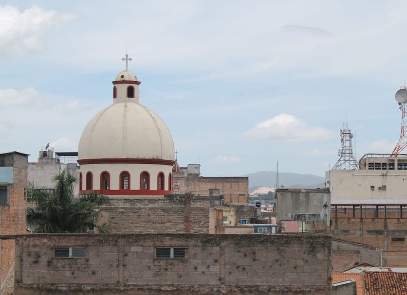 Hotel Mac Arthur in Tegucigalpa with rooftop city view and a white domed church