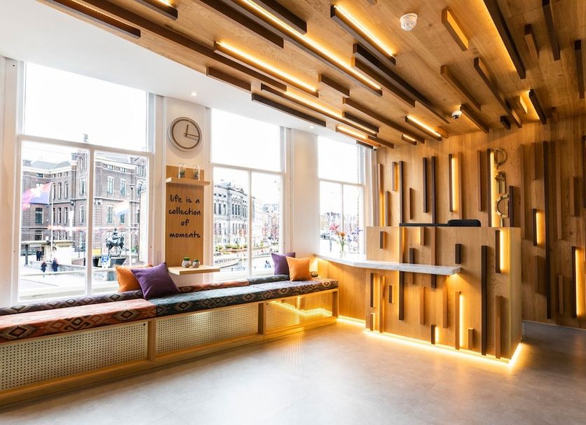 Hotel Pagi, Amsterdam lobby with bench seating, warm wood ceiling lights and large street-view windows