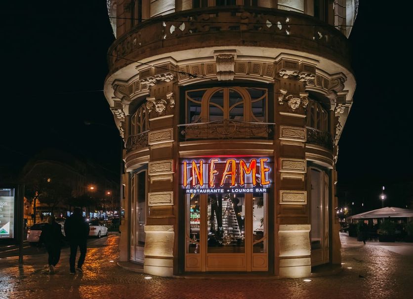 1908 Lisboa Hotel in Lisbon at night, showing ornate corner facade and neon sign on a wet street