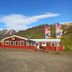 Engimyri Lodge in Akureyri, red lodge with mountain backdrop and gravel forecourt