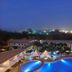 Golden Tulip Kumasi City in Kumasi, lit outdoor pool terrace at night with city skyline view