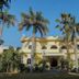 Raj Palace Resort in Sawāi Mādhopur, a yellow villa-style hotel framed by tall palm trees