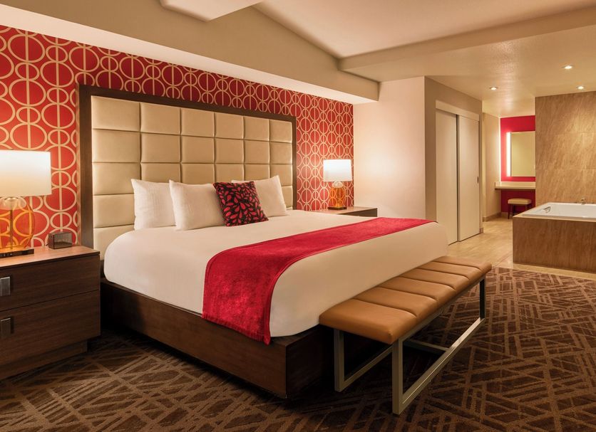 Horseshoe Las Vegas guest room with king bed, bench, soaking tub, and modern carpeted interior