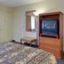 Vagabond Inn Ventura room with TV cabinet, floor lamp, bench and mini fridge in Ventura