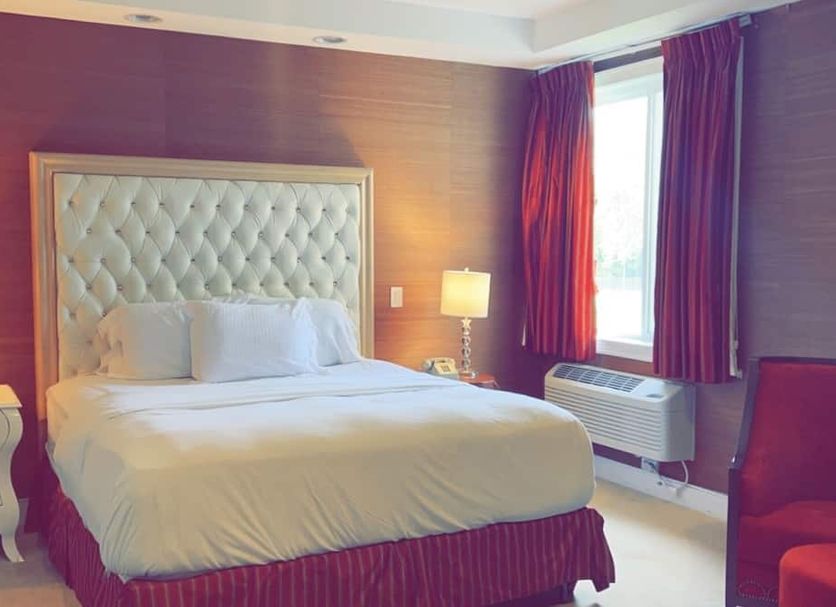 Rocky River Inn in New Milford guest room with tufted headboard, bed, window and red curtains