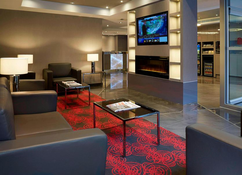 Residence Inn by Marriott Montreal Downtown lobby with sofas, red patterned rug, and wall-mounted TV