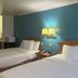 Motel 6 Portland, IN room with two beds, teal accent wall, and bedside lamp