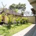 Tanjung Alam Hotel in Buleleng courtyard with palm trees, lawn, paved walkways, and tiled-roof buildings
