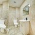 Belvilla Ilford Station Hotel bathroom with bathtub, toilet, sink and beige tile walls in Ilford