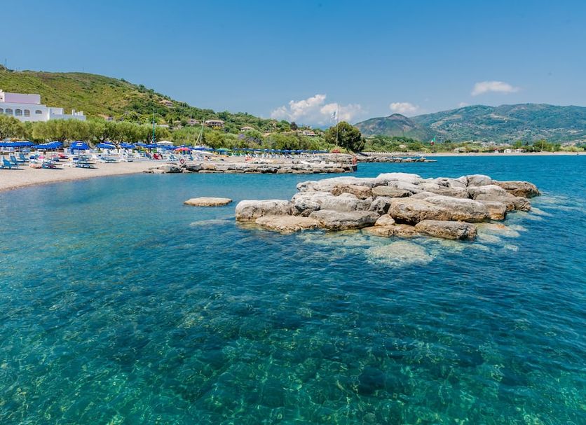 Hotel Torre Oliva in San Giovanni a Piro with clear turquoise sea, rocky shoreline and beach loungers