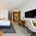 Clarion Hotel Jeddah Airport room with king bed, sofa, desk and wall-mounted TV in Jeddah