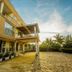 Hotel Royal Nest in Entebbe exterior with balcony, covered entrance, and palm-lined driveway