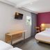 B&B HOTEL Le Puy-En-Velay room with double bed, wall-mounted TV, desk, and magenta accent wall