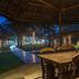 Chariot Beach Resort in Mahabalipuram with a thatched outdoor dining table under a pavilion at dusk