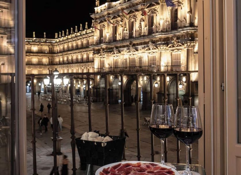 Salamanca Luxury Plaza in Salamanca, night view of illuminated historic plaza with wine glasses by the window