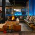 Moxy Milton Keynes lounge with fireplace, hanging chair, sofa seating and city-view windows