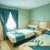 Alaxis Hotel Kuala Lumpur room with two beds, teal bedding, and curtains by a bright window