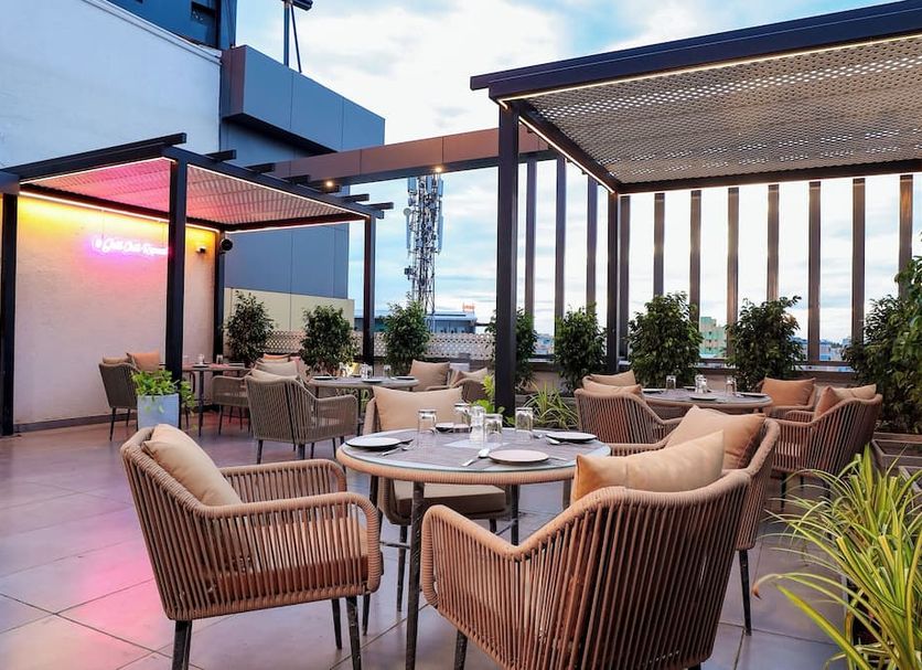 Sathyam Oasis, Tiruchirappalli: rooftop terrace dining area with seating, pergola shade and city view