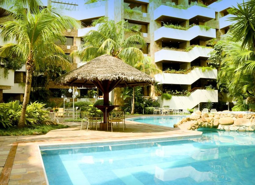 Yotau All Suites Hotel in Santa Cruz de la Sierra with palm-lined pool and thatched poolside bar