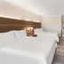 Holiday Inn Express & Suites Byron By IHG guest room with three beds, wood headboard and TV in Byron