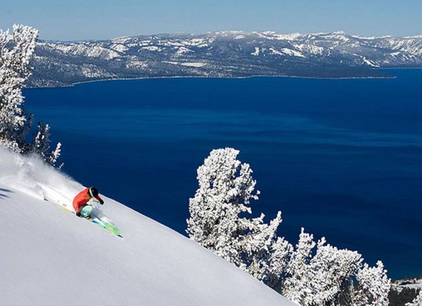 Hotel Azure in South Lake Tahoe with a skier on a snowy slope above a blue lake and mountains