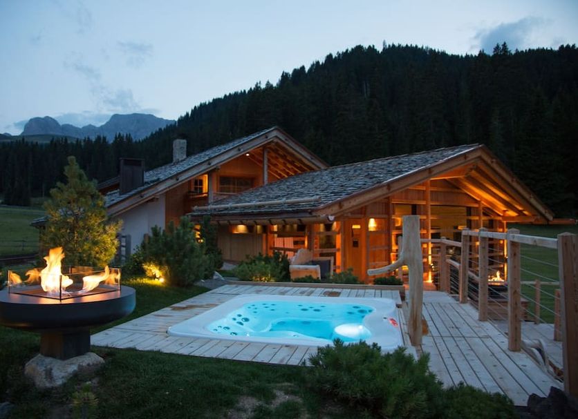 Dolomites Living Hotel Tirler in Castelrotto with outdoor hot tub, fire pit, and mountain chalet setting