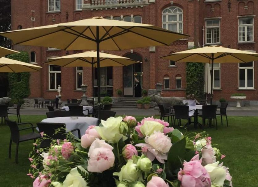Hotel Lodewijk Van Male in Bruges courtyard with tables, umbrellas, and a bouquet of pink flowers