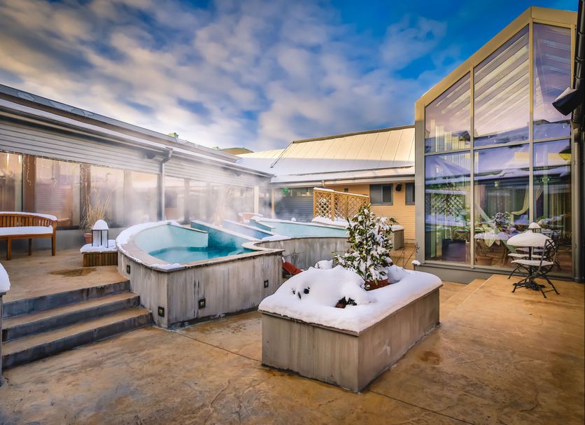 Vadstena Klosterhotel in Vadstena with an outdoor hot tub and snowy courtyard beside glass buildings