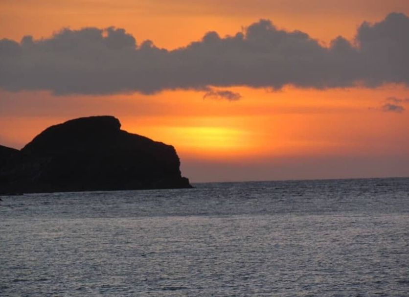 Newberry Beach Lodge in Ilfracombe with a sunset over the sea and a rocky headland silhouette