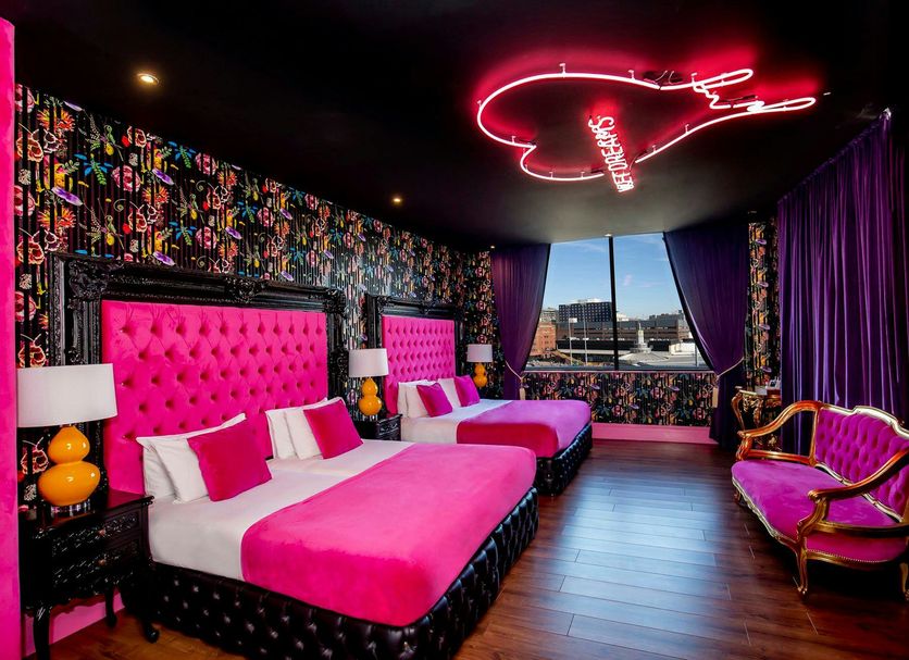 The Shankly Hotel Liverpool room with two pink beds, neon ceiling light and city view