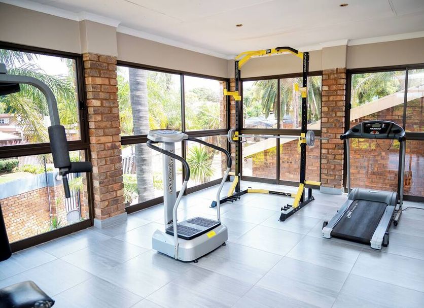 Boksburg Boutique Hotel gym in Boksburg with treadmill, step platform and weight station by large windows