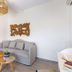 Dolphin Bay Seaside Resort & Suites in Galissas living area with gray sofa, nesting tables and bedroom doorway
