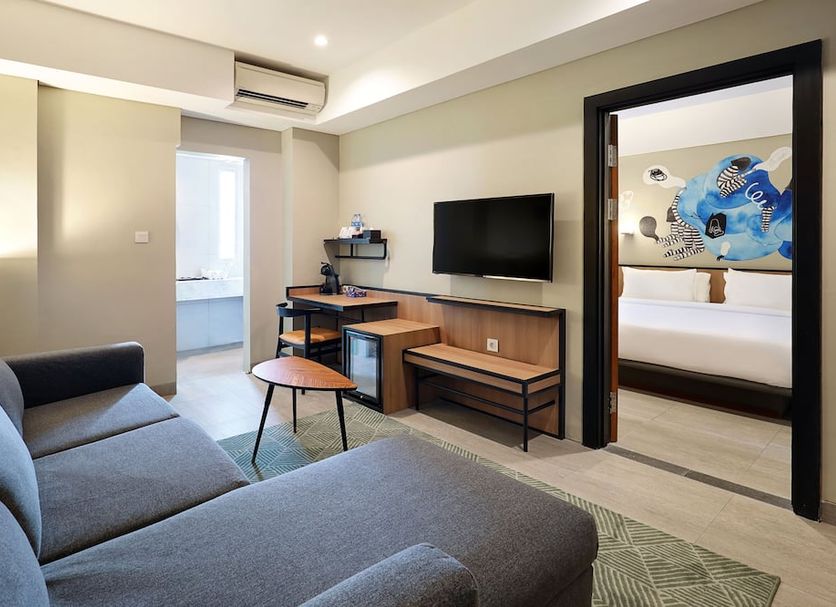 Swiss-Belinn Wahid Hasyim Jakarta living area with sofa, TV, desk and doorway to bedroom