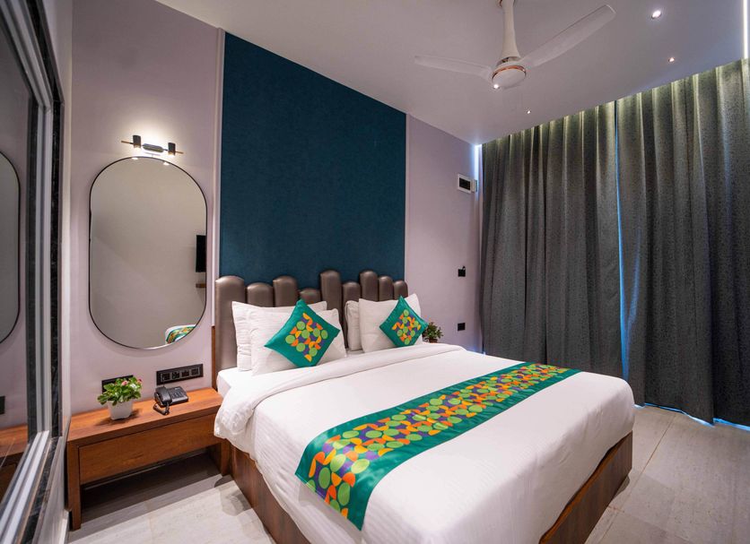 Treebo Winter Town Venna Lake bedroom in Mahabaleshwar with a bed, side table, mirror, and floor-to-ceiling curtains
