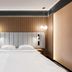 Artis Loft Hotel Mszczonów room with king bed, wall lights and modern wood slat headboard