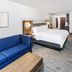 Holiday Inn Express & Suites Dumas By IHG guest room with king bed, blue sofa and work desk