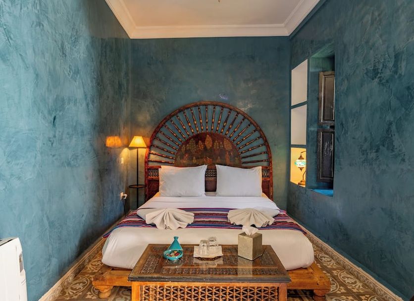 Riad Yamina52 Marrakech guest room with bed, blue walls, and carved headboard