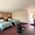 Knights Inn Kirksville guest room with two beds, seating area, desk, and hallway view
