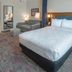 Home2 Suites by Hilton Saratoga Malta guest room with king bed, sofa, floor mirror and lamps