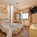 Agriturismo La Meria in Semproniano bedroom with four-poster bed, wall-mounted TV and countryside window view