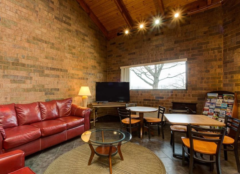 Skylight Inn Cleveland - Willoughby lounge with red leather sofa, TV, tables and brick walls