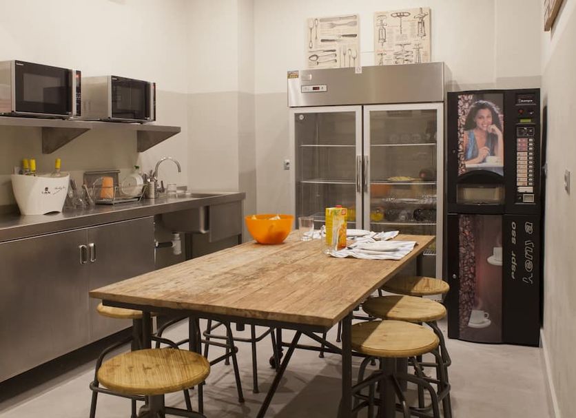 Malaga Stop Hostel Ab in Málaga shared kitchen with stainless steel counters, dining table, fridge, and vending machine