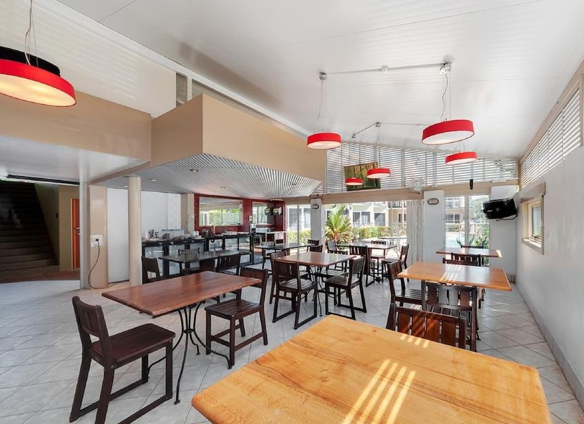 Tropical Queenslander in Cairns breakfast dining area with tables, chairs, and red pendant lights