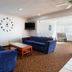 Motel 6 El Paso - Southeast lobby seating area with blue sofas, wall clock and TV
