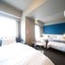 Dormy Inn Miyazaki Natural Hot Spring room with three beds, window light, and blue accent wall