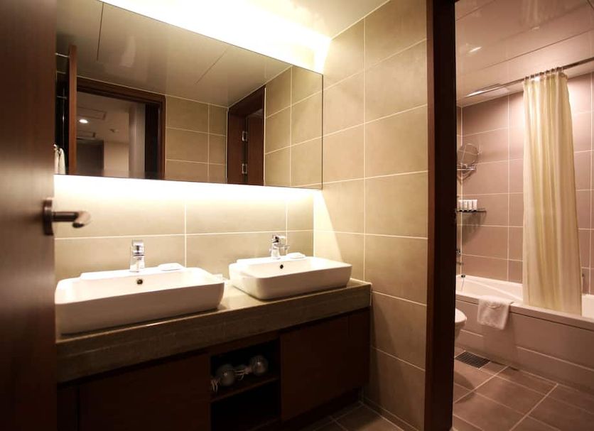 Hotel Skypark Myeongdong Ii bathroom in Seoul with double sinks and a shower-over-tub behind a curtain