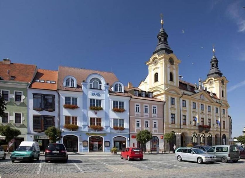 Hotel City Pisek in Písek with historic square, ornate towers, and parked cars under a blue sky