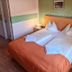 Pension Göschlberger in Mondsee bedroom with twin beds, orange bedspread, and bedside lamps